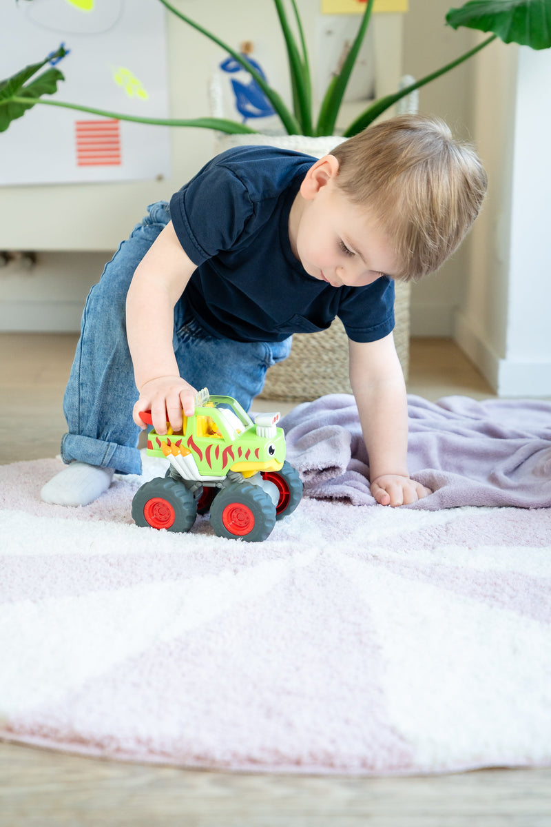 Toddler playing with WOW Toys Mack Monster Truck on a rug
