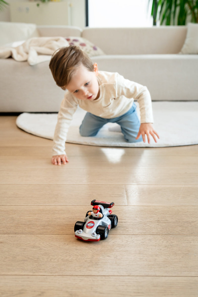 Baby crawling after WOW Toys Richie Race Car