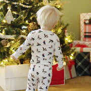 Child wearing Saltwater Swaddles Duck the Halls pajamas standing near Christmas tree in festive room