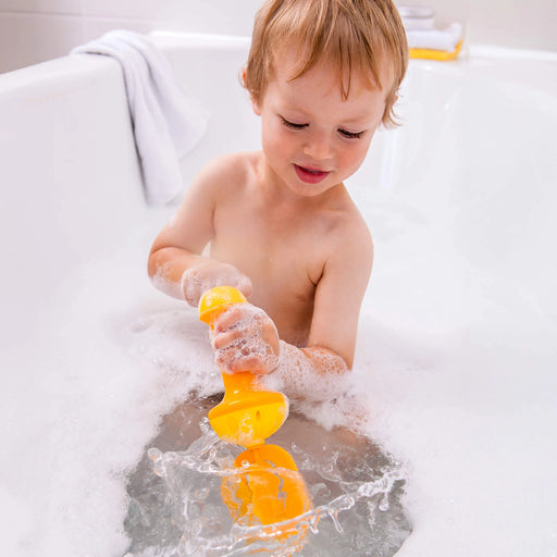 Child playing with a yellow bath toy in a bathtub filled with bubbles
