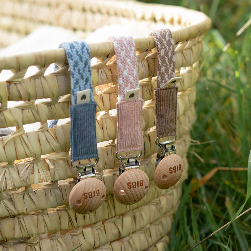 BIBS pacifier clips attached to a woven basket, demonstrating everyday use