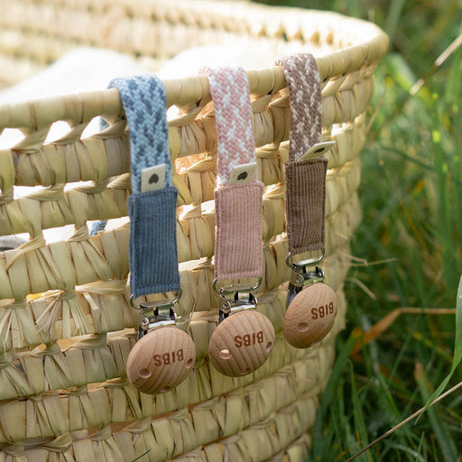 BIBS pacifier clips attached to a woven basket, demonstrating everyday use