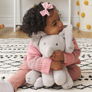 Toddler hugging Flappy the Elephant plush on a nursery rug